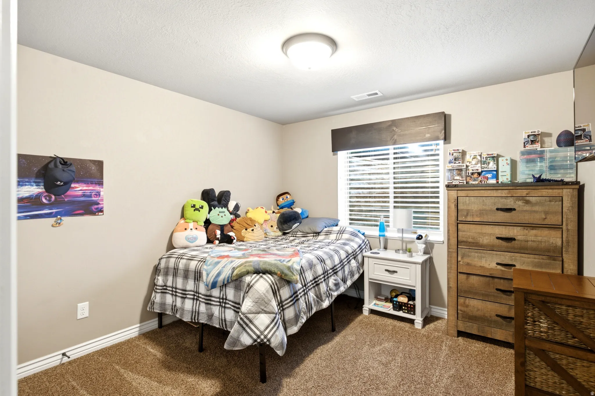 Carpeted room with a ceiling-mounted light fixture, window with horizontal blinds, and a wood valance