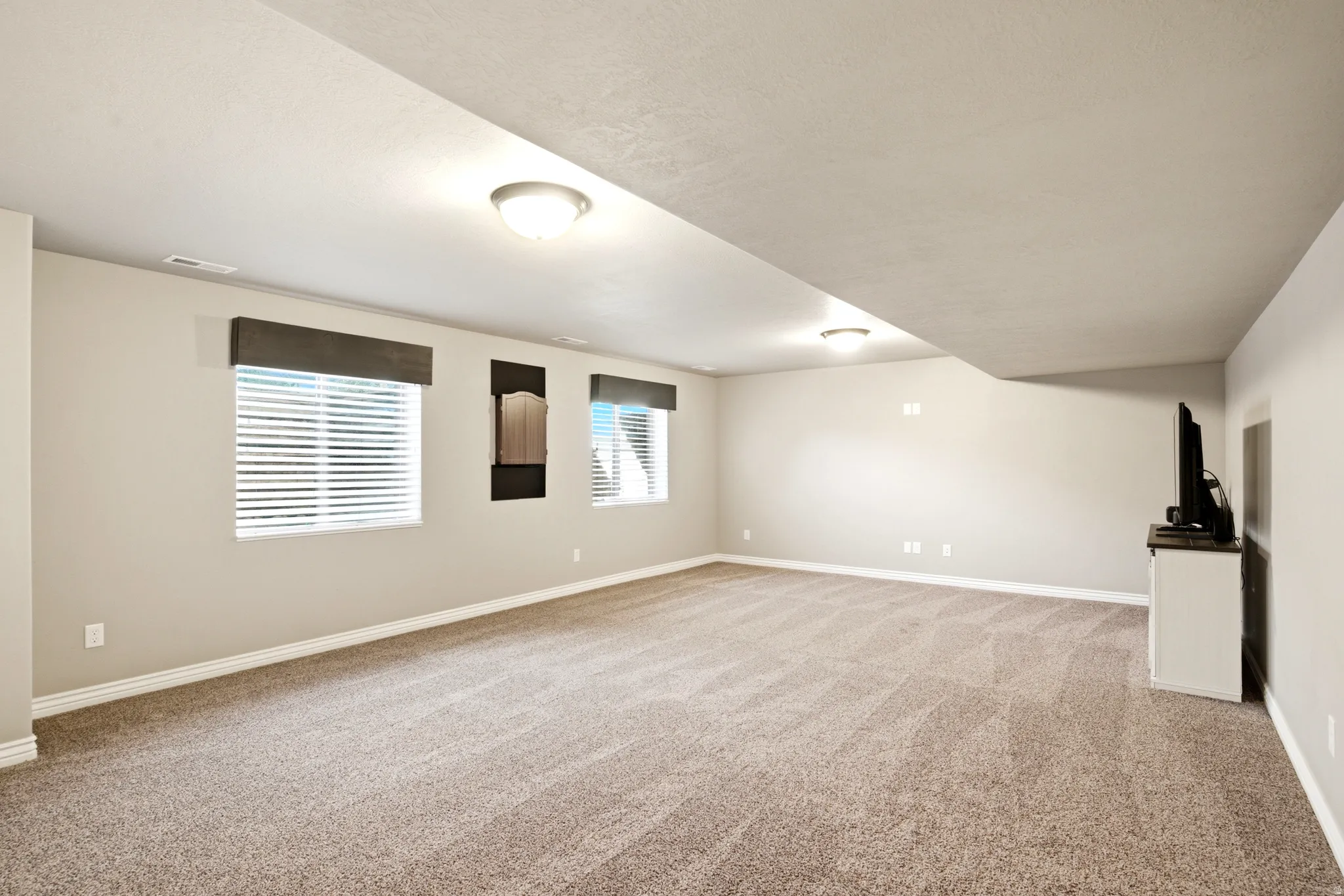 Expansive room featuring neutral-toned carpet, recessed lighting, and multiple windows with blinds