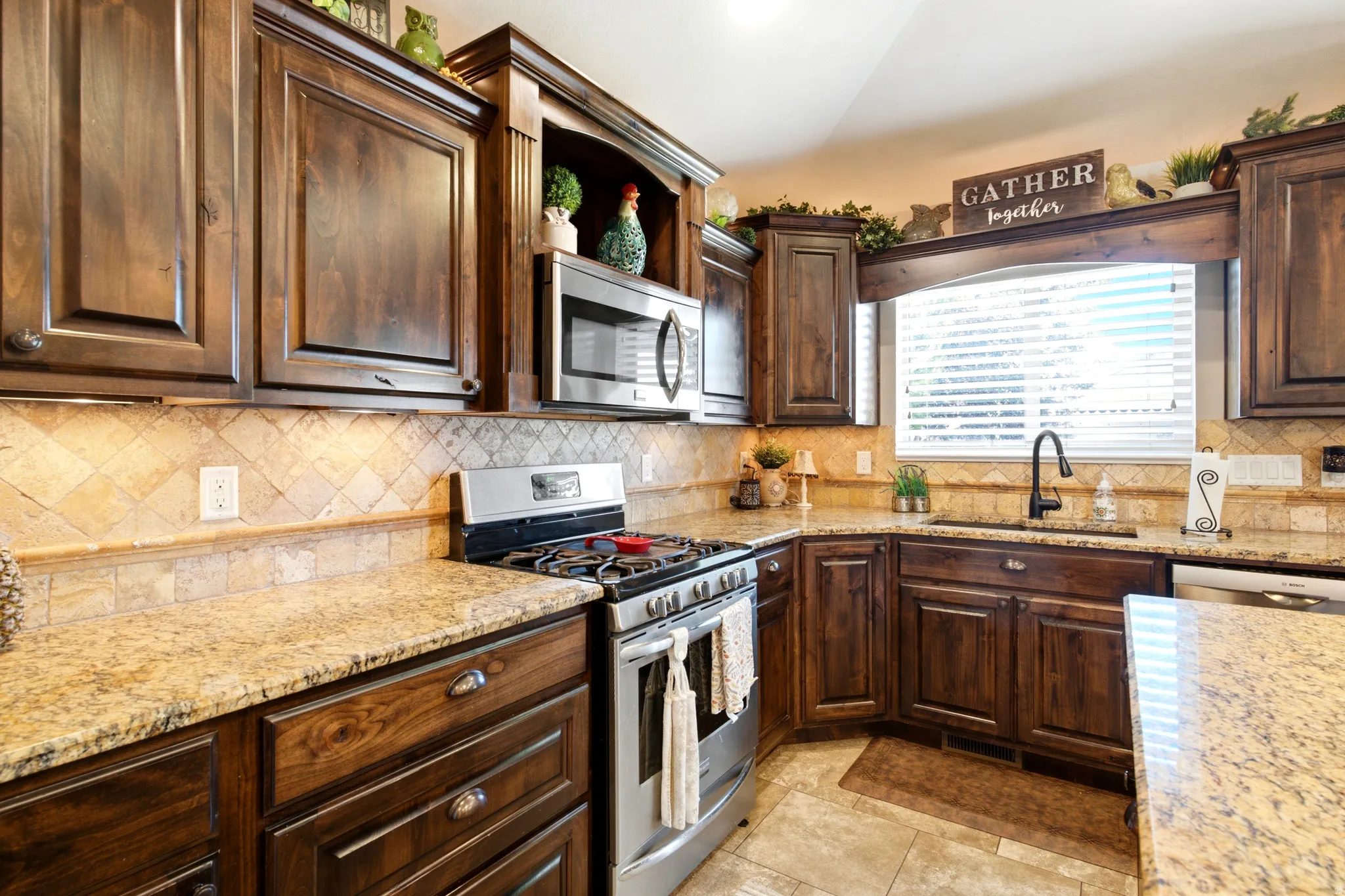 Dark wood-finish cabinetry, light-toned stone countertops, stainless steel appliances, and a tiled backsplash