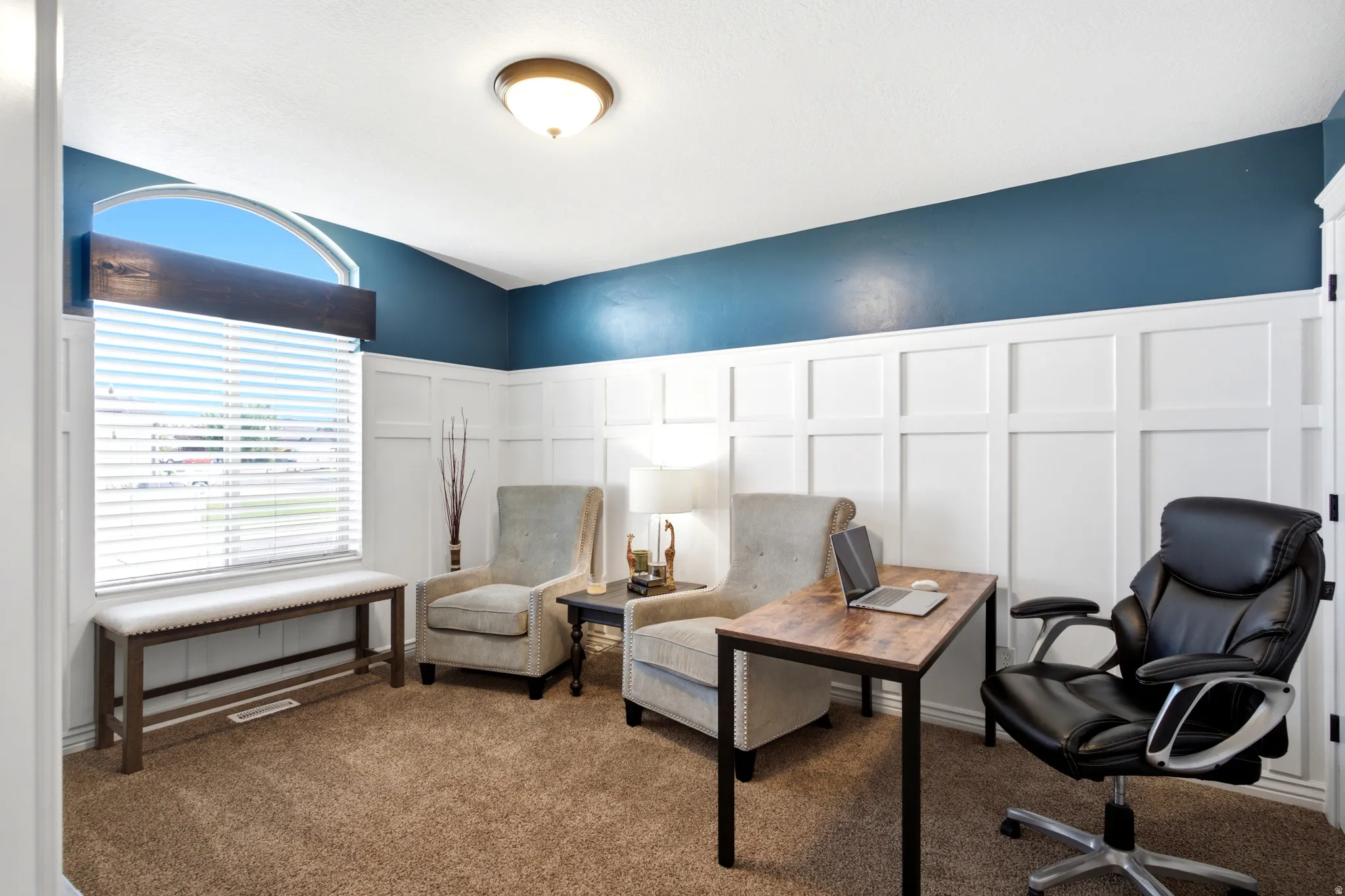 Arch-top window with blinds, board and batten wall detailing, wall-mounted ceiling light fixture, and plush carpeting