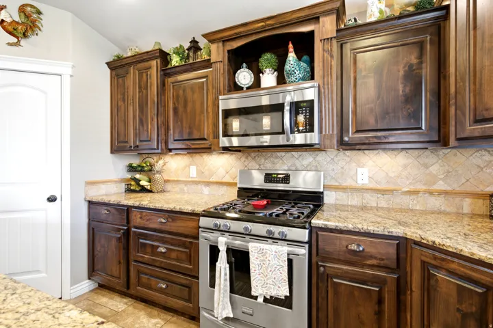 Wood-finish cabinetry, stainless steel appliances, granite countertops, and tile backsplash