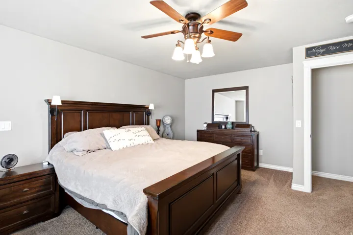 Ceiling fan with integrated lighting, recessed wall sconces, wall-to-wall carpeting, and an open doorway