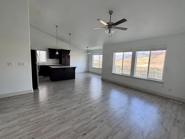 Open-concept living space with vaulted ceilings, wood-finish flooring, and multiple windows
