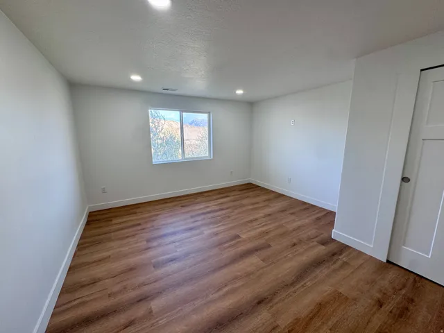 Recessed lighting, wood-finish flooring, white walls, and a window with natural light