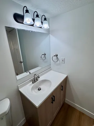 Vanity with a white countertop and integrated sink, wood-finish cabinetry, and black hardware