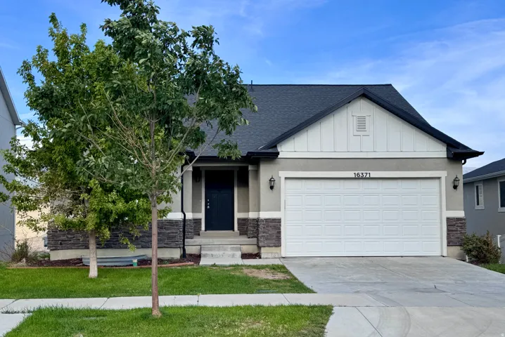 Attached two-car garage with a concrete driveway, stone facade details, and a dark asphalt shingle roof
