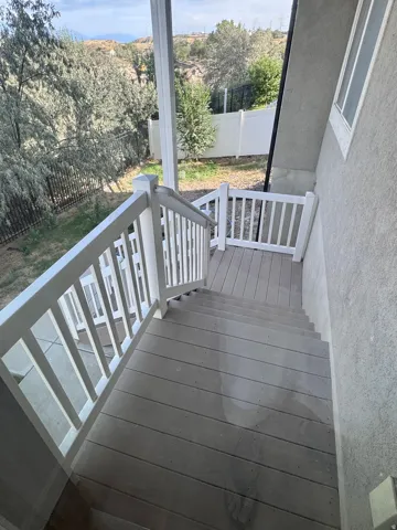 Outdoor deck with composite decking, white railings, and a security gate
