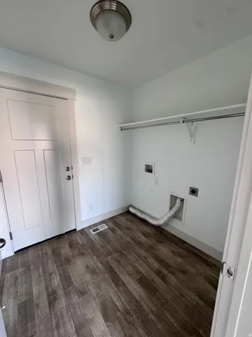 Wood-finish flooring, white walls, flush-mount ceiling light, white paneled door, and a built-in wire shelf