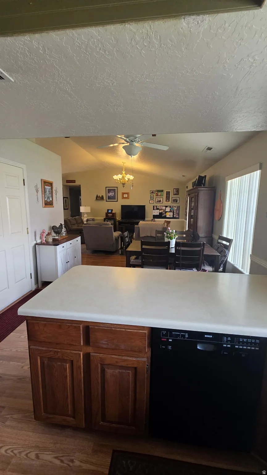 Kitchen island with a light-toned countertop, wood-finish cabinetry, and a built-in dishwasher