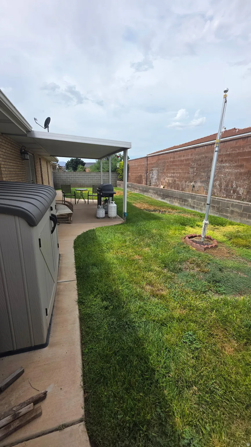 Patio area with an overhead cover, concrete pathway, and a grassy yard