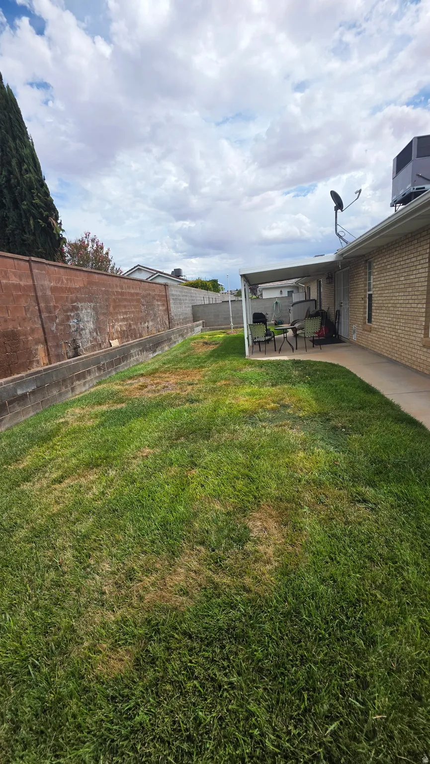 Backyard with a covered patio, brick wall, and mature perimeter trees