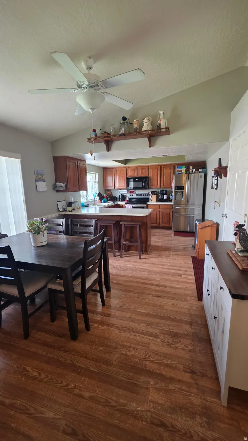 Vaulted ceiling, wood-finish flooring, ceiling fan, wood cabinetry, built-in kitchen island with seating