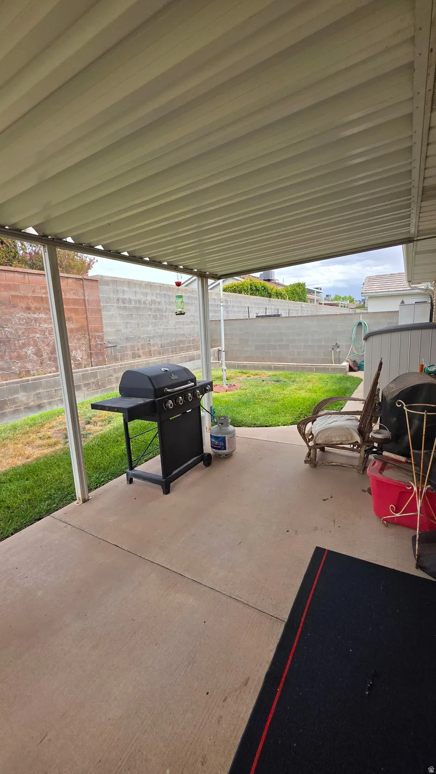 Patio with a solid overhead covering, concrete flooring, and a grassy yard area