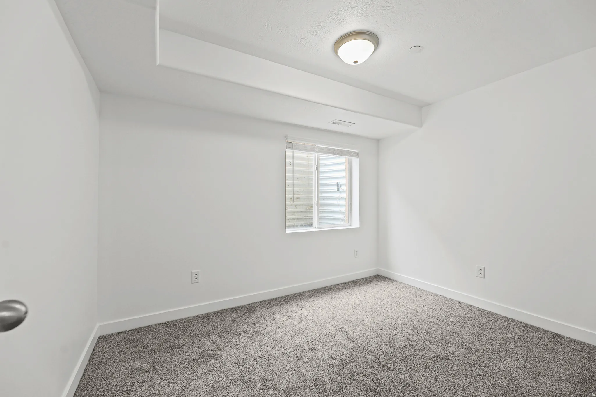 Neutral wall paint, recessed lighting, flush-mount ceiling light, window with blinds, and gray carpeting