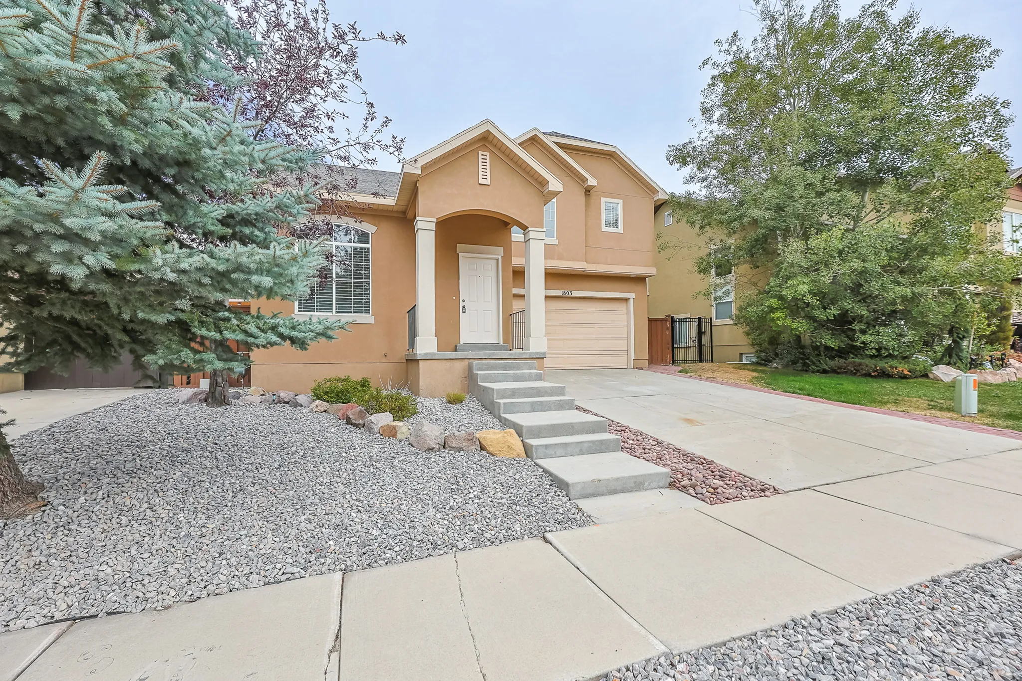 Stucco exterior with a columned front porch, concrete steps, and an attached garage