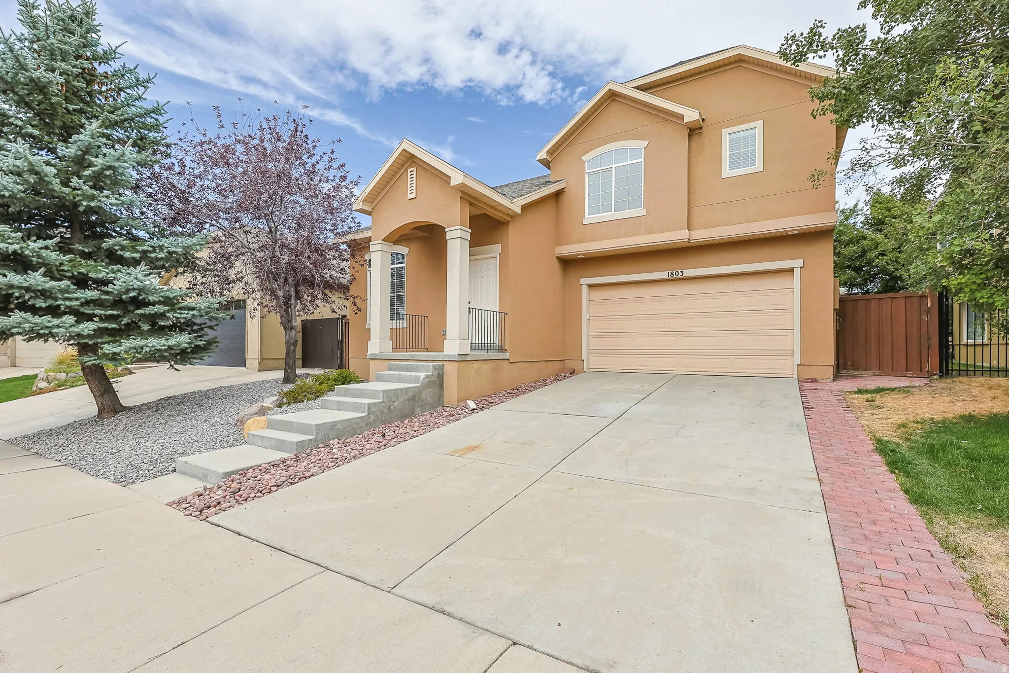 Stucco exterior with an arched entry, columned porch, and a two-car garage