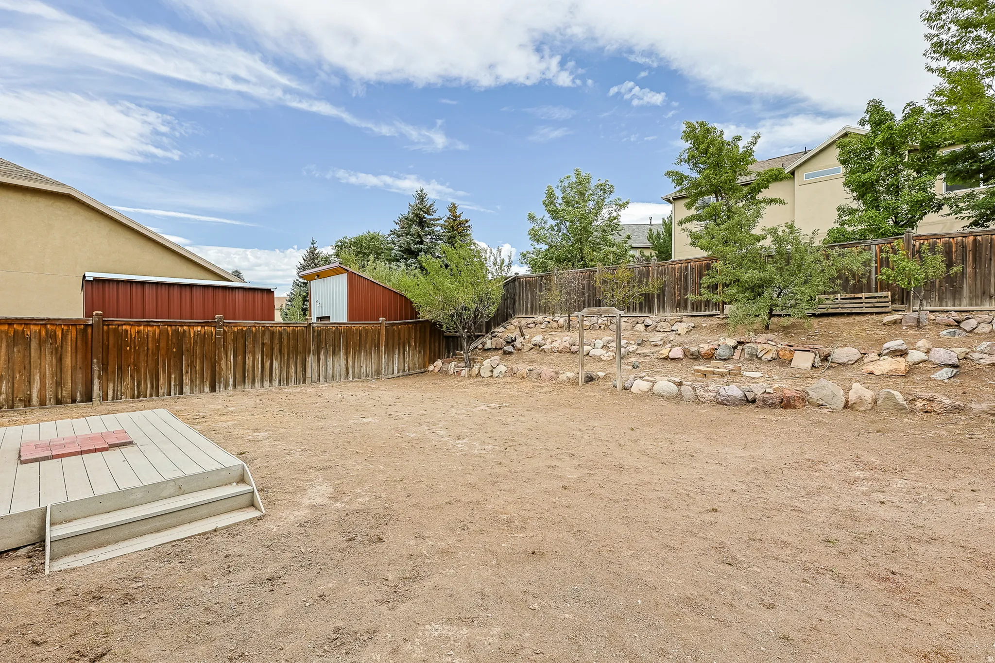 Terraced landscaping with rock accents, wood fencing, and a built-in storage shed