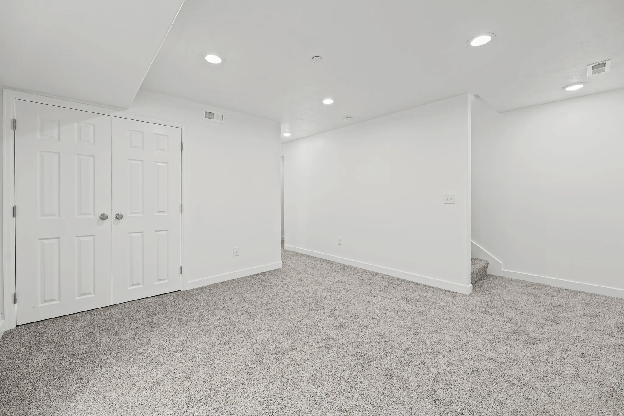 Recessed lighting, plush carpeting, bi-fold panel doors, and a neutral color palette