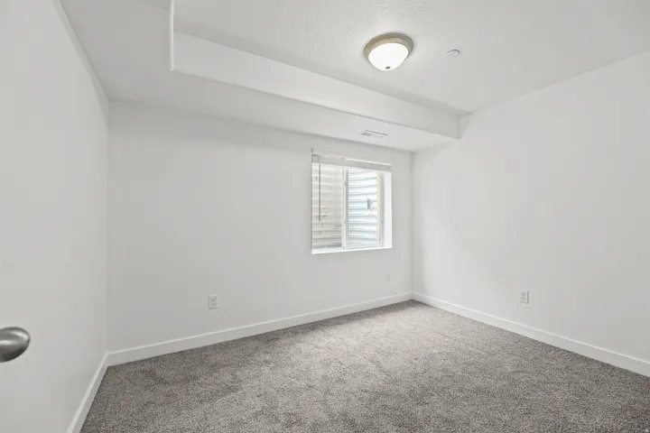 Neutral wall paint, recessed lighting, flush-mount ceiling light, window with blinds, and gray carpeting