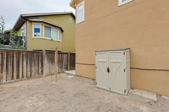 Enclosed side yard with a wood fence and a beige storage shed