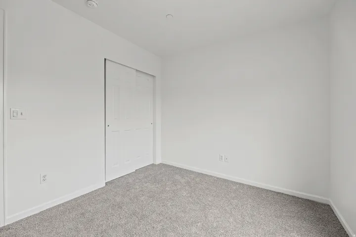 Carpeted flooring, white walls, and a white sliding closet door