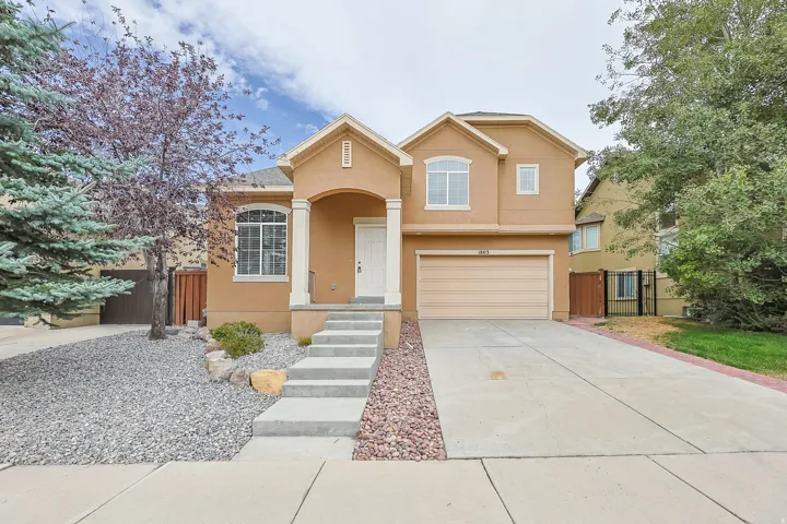 Stucco exterior with arched entry, attached garage, and concrete driveway