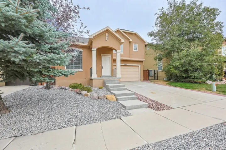 Stucco exterior with a columned front porch, concrete steps, and an attached garage