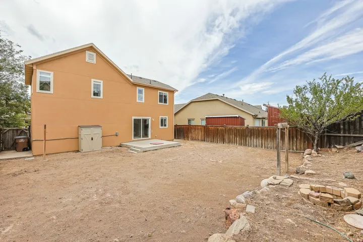 Stucco exterior with multiple windows, concrete patio, and a built-in fire pit