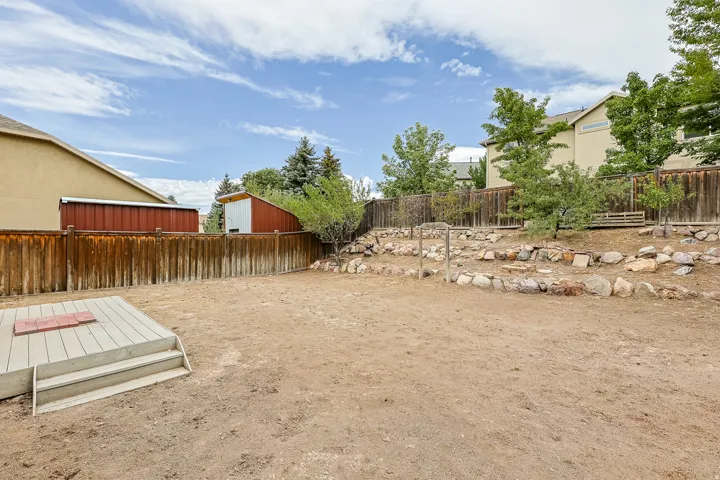 Terraced landscaping with rock accents, wood fencing, and a built-in storage shed