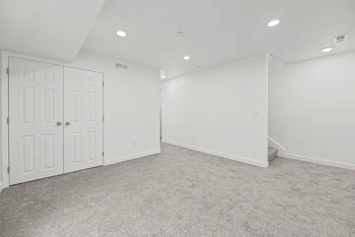 Recessed lighting, plush carpeting, bi-fold panel doors, and a neutral color palette