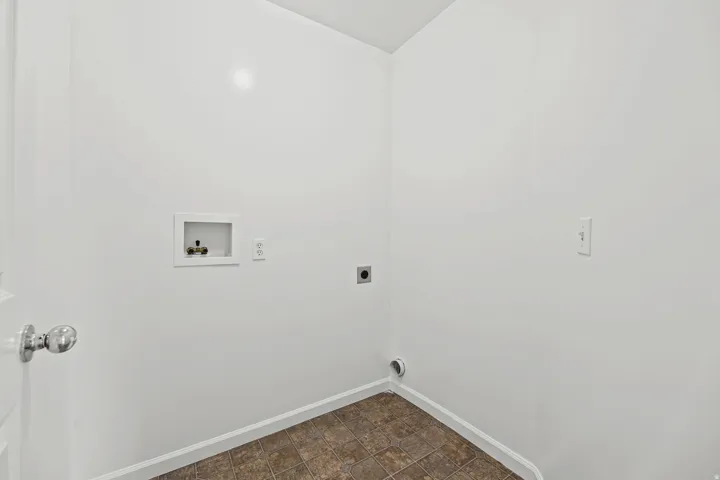 Dedicated utility space featuring tile-look flooring, white walls, and essential hookups for appliances