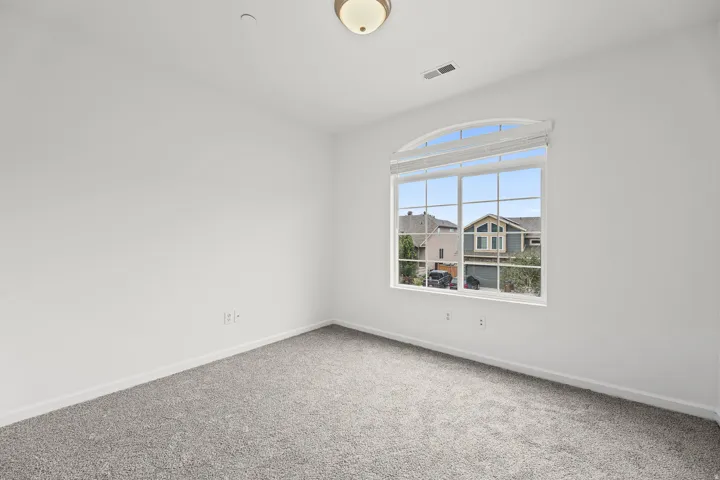 Room featuring a large arched window with horizontal blinds, grey carpet, and a flush mount ceiling light