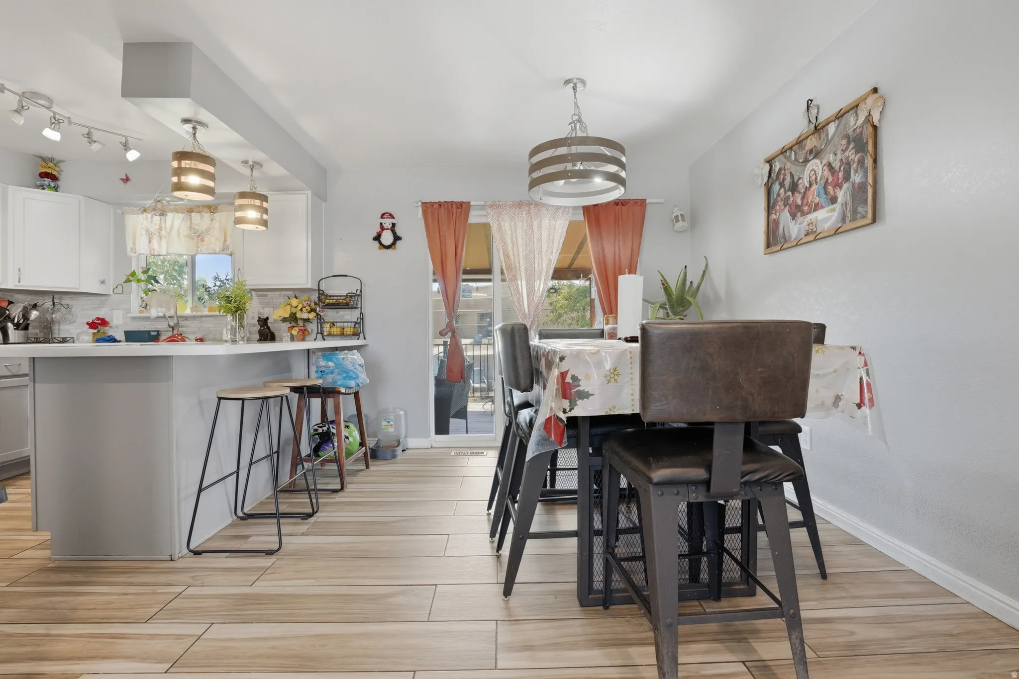 Light wood-finish flooring, white cabinetry, track lighting, and a glass sliding door
