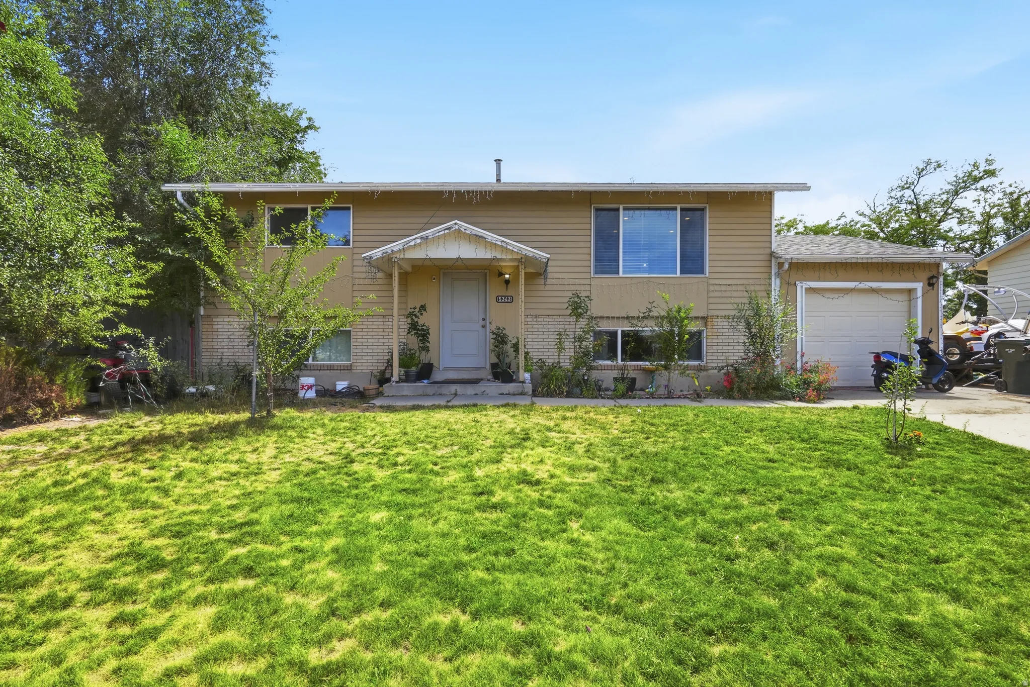 Two-story exterior with horizontal siding and brick accents, featuring a covered entry, attached garage, and mature landscaping