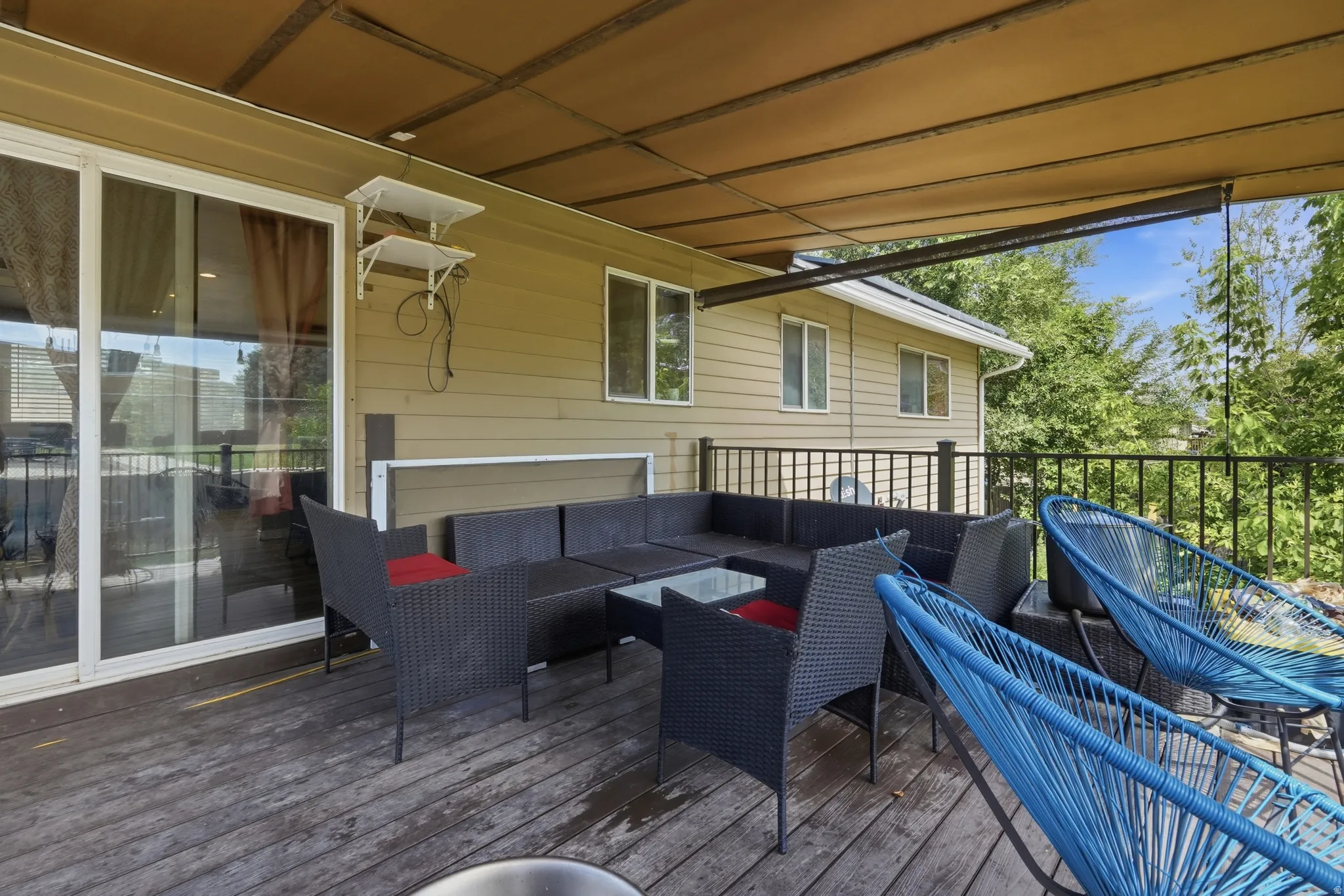 Covered outdoor deck with wood flooring and a black railing