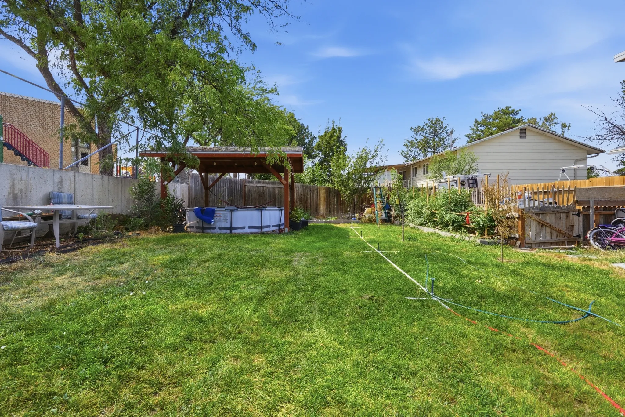 Expansive backyard featuring a lush lawn, a wood-frame gazebo, and mature trees