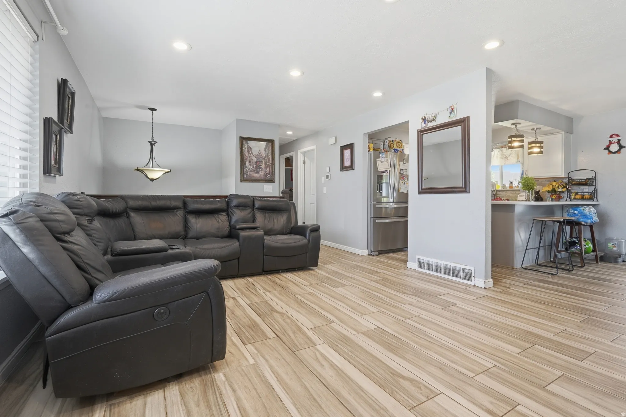 Wood-finish flooring, recessed ceiling lighting, and a kitchen pass-through with pendant lighting