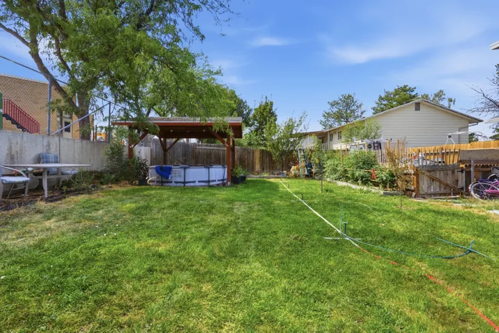 Expansive backyard featuring a lush lawn, a wood-frame gazebo, and mature trees