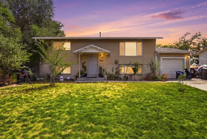 Split-level residence featuring a covered front entry, attached garage, and a level lawn area
