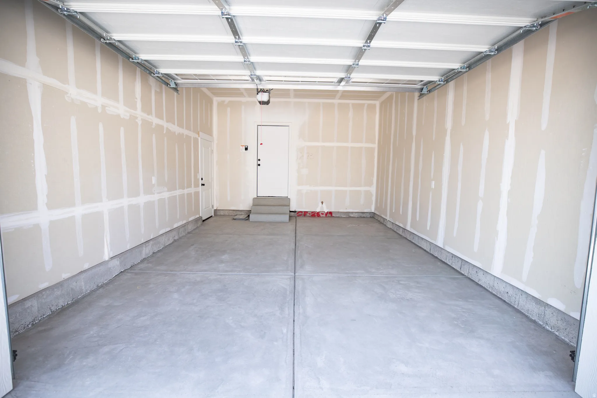 Extra-wide one car garage with service door and taped finish.