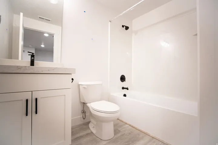 Full secondary bath #2 with painted white wood cabinets, quartz slab countertops in fully-finished basement.