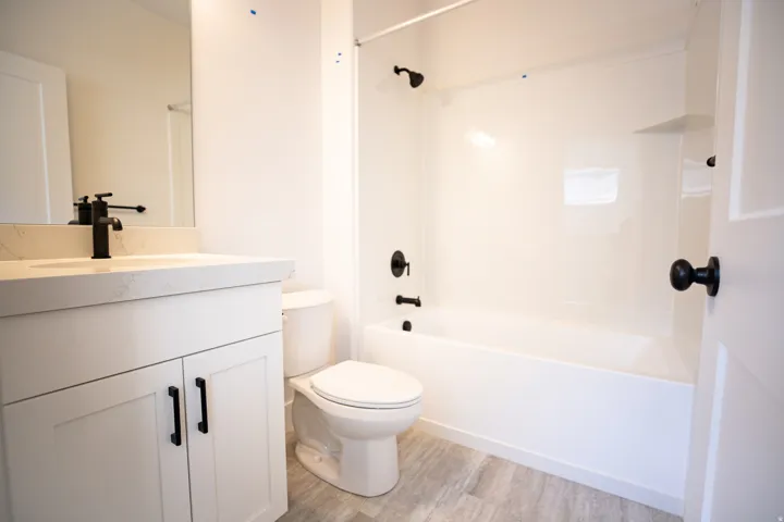 Full secondary bath #1with painted white wood cabinets and quartz slab countertops.