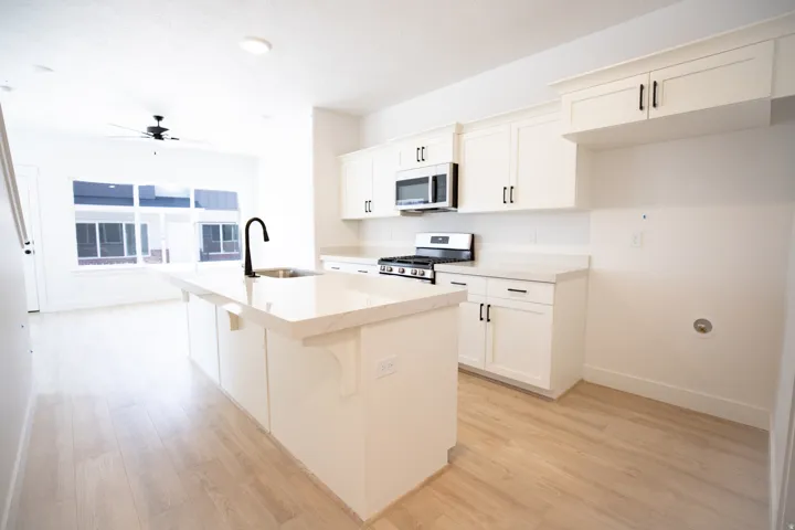 Terrific kitchen with painted white wood cabinets, long serving island, quartz slab countertops, walk-in pantry, gas range, microwave, built-in dishwasher and disposal.