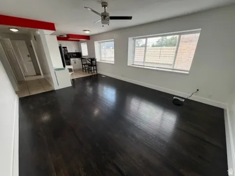 Wood-finish flooring, white walls, and a ceiling fan with integrated lighting