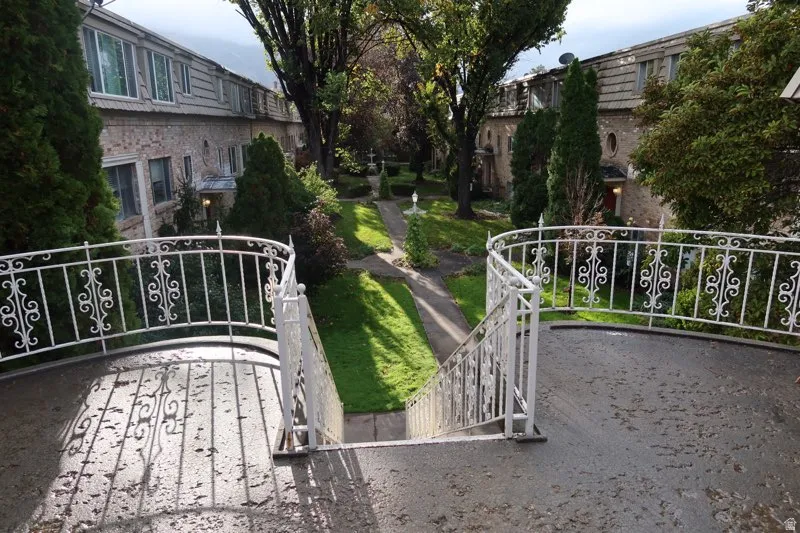 Stone exterior buildings with decorative white railings and mature trees framing a central pathway