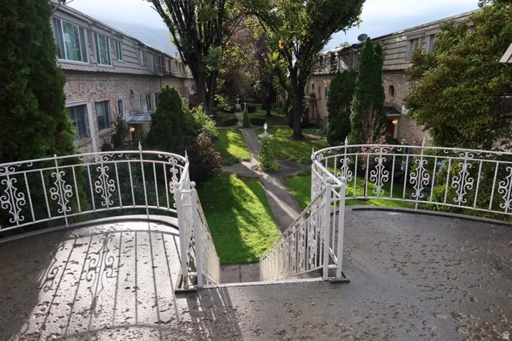 Stone exterior buildings with decorative white railings and mature trees framing a central pathway