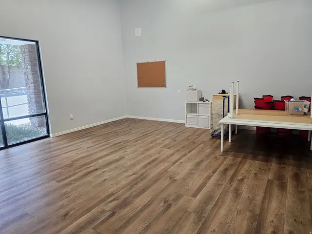 Wood-finish flooring, tall ceilings, and large window with dark trim