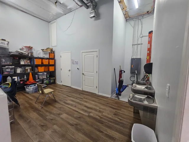 High ceilings with exposed ductwork, wood-finish flooring, two panel doors, and built-in drinking fountains