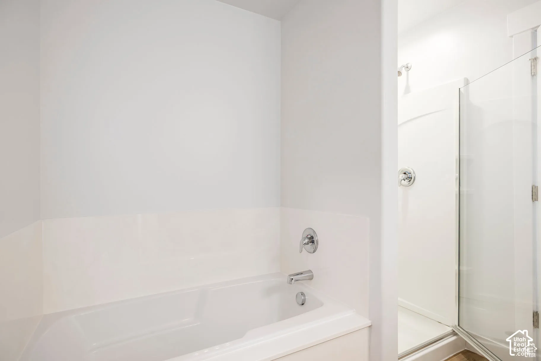 White integrated bathtub with chrome fixtures and an adjacent standing shower with a clear glass enclosure