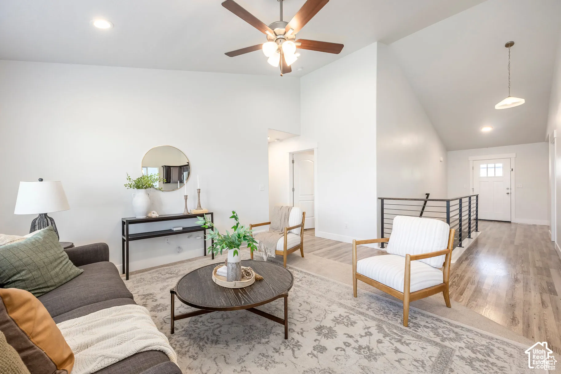Vaulted ceiling, ceiling fan with integrated lighting, wood-finish flooring, recessed lighting, and a metal stair railing